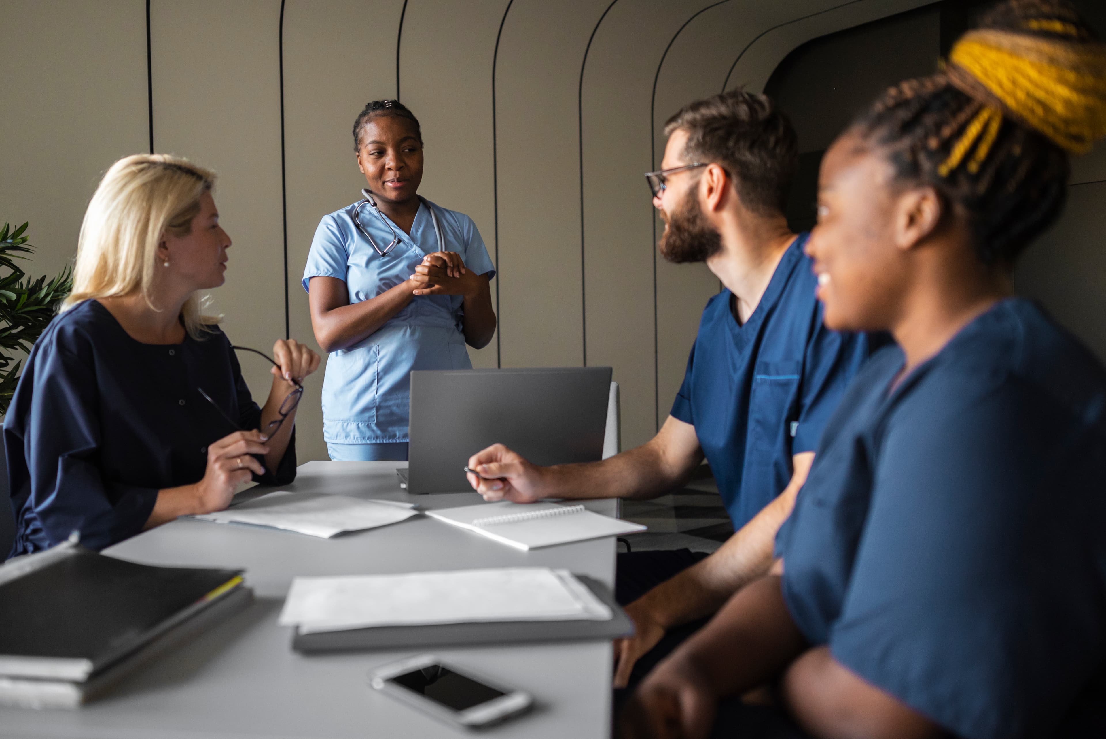 Nurses gathered around a table sharing input during a structured well-being needs assessment